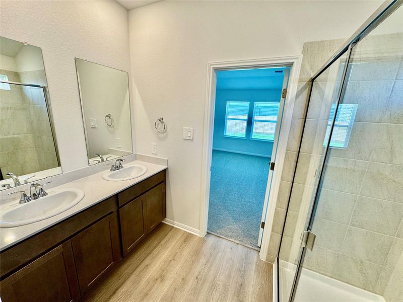 Full bathroom with wood finished floors, a shower stall, and double vanity