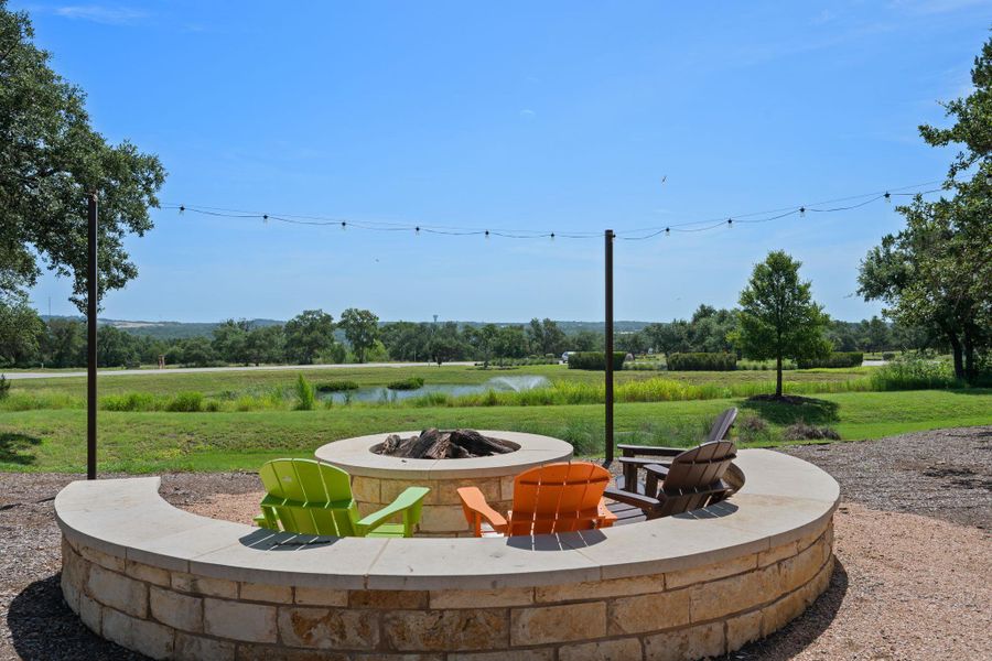 View of grassy yard featuring a water view, a fire pit, and a patio area View of grassy yard featuring a water view, a fire pit, and a patio area