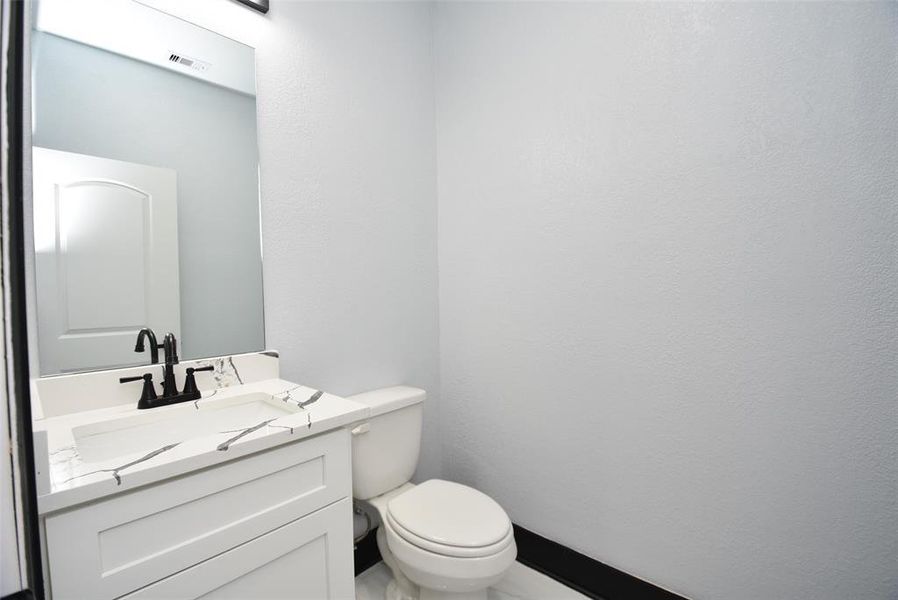 his half bathroom features a sleek quartz countertop.