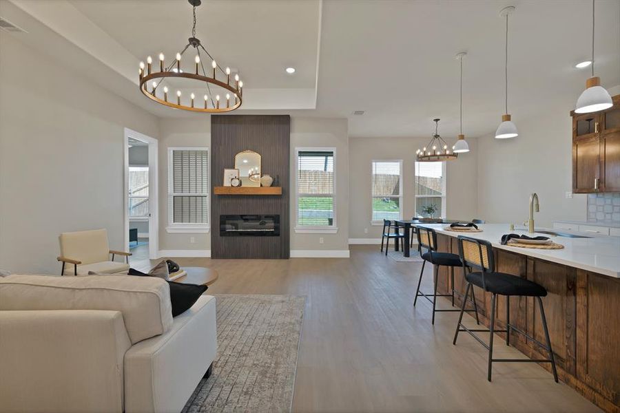 Living area with a chandelier, light wood-style flooring, a large fireplace, baseboards, and recessed lighting