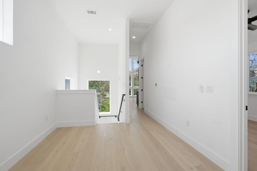 Hall with light wood finished floors, an upstairs landing, and recessed lighting