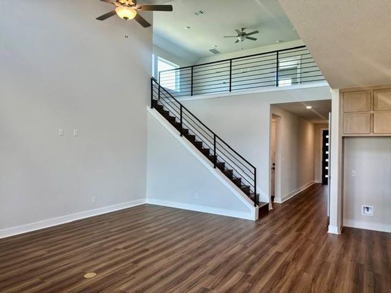 A spacious common area with high ceilings, warm wood flooring, and an elegant staircase leading to a functional loft. A spacious common area with high ceilings, warm wood flooring, and an elegant staircase leading to a functional loft.