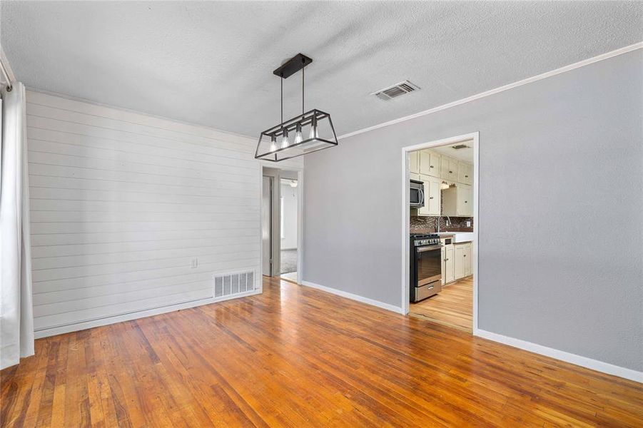 Dining room with hardwood floors, decorative lighting, and shiplap wall Dining room with hardwood floors, decorative lighting, and shiplap wall