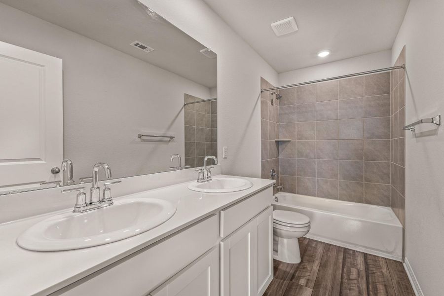 Bathroom with shower / bathtub combination, dark wood-style flooring, and double vanity Bathroom with shower / bathtub combination, dark wood-style flooring, and double vanity