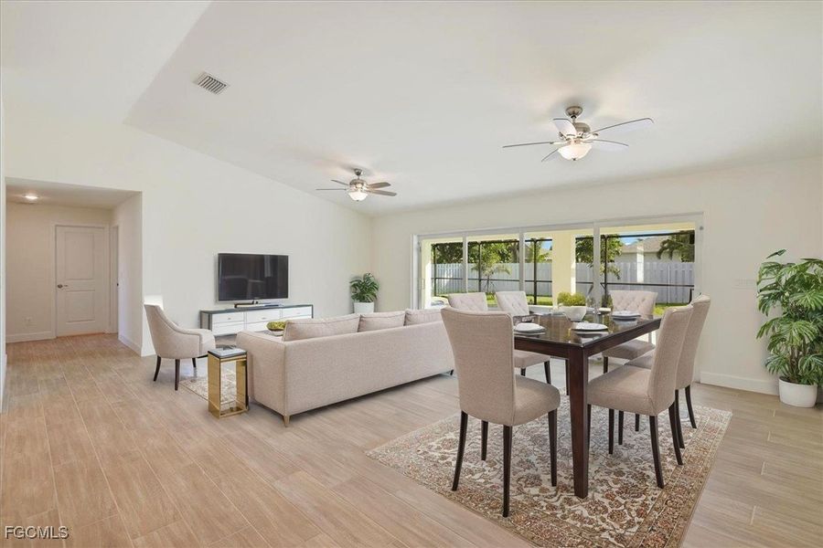 Dining space with lofted ceiling, a ceiling fan, and light wood-type flooring