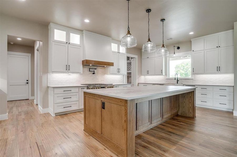 Kitchen featuring premium range hood, a center island, decorative backsplash, recessed lighting, and white cabinets Kitchen featuring premium range hood, a center island, decorative backsplash, recessed lighting, and white cabinets