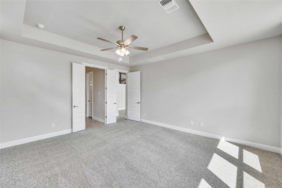 Unfurnished bedroom featuring a tray ceiling, light carpet, and ceiling fan Unfurnished bedroom featuring a tray ceiling, light carpet, and ceiling fan