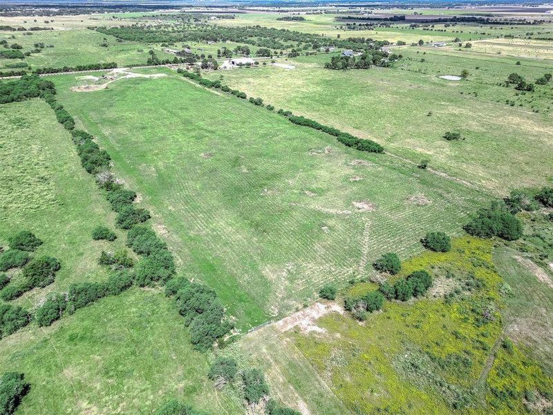 Aerial view of the homesite showing open pastureland, natural tree lines, and surrounding rural acreage.