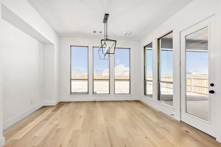 Unfurnished dining area featuring light wood finished floors and a chandelier