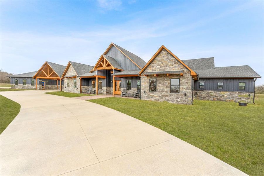 View of front facade featuring stone siding, a shingled roof, and board and batten siding