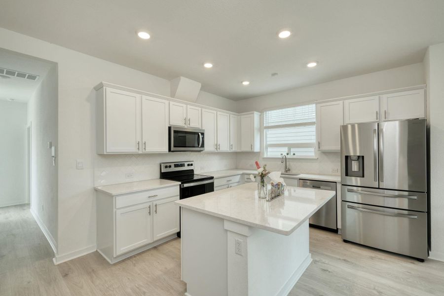 Kitchen with light wood finished floors, visible vents, appliances with stainless steel finishes, and white cabinets