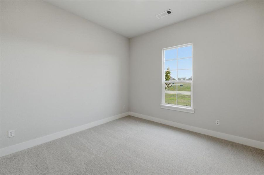 This room features neutral-toned carpeting and walls, complemented by a white window frame and baseboards