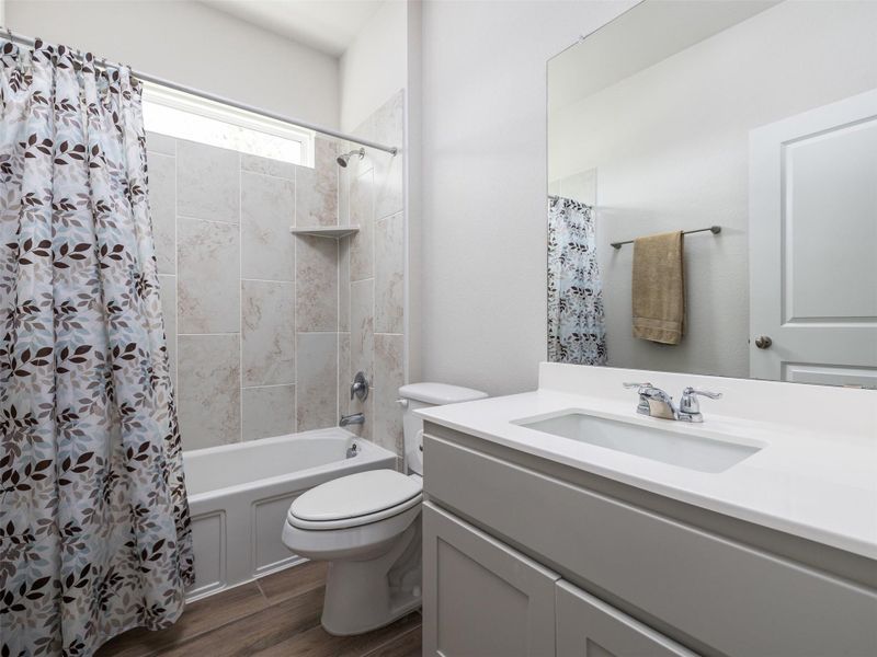 Full bathroom with vanity, shower / tub combo with curtain, and dark wood finished floors