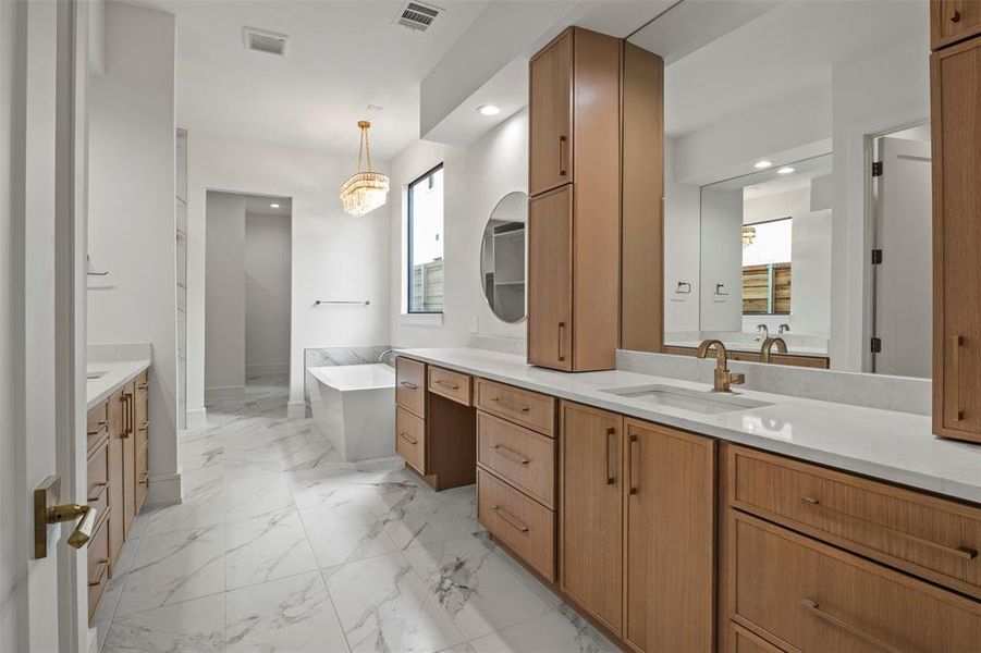Bathroom with a soaking tub, two vanities, light marble finish floors, recessed lighting, and a chandelier Bathroom with a soaking tub, two vanities, light marble finish floors, recessed lighting, and a chandelier