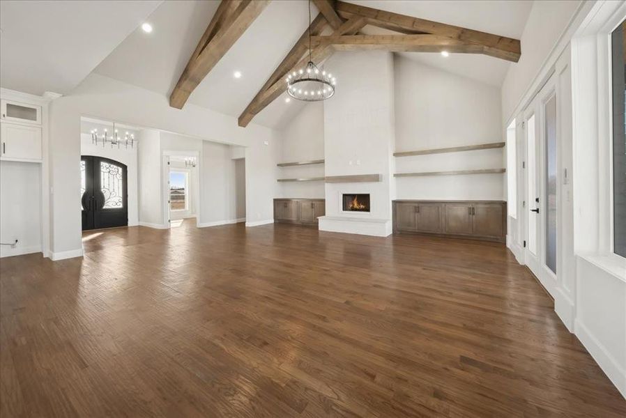 Unfurnished living room with french doors, dark wood-type flooring, beam ceiling, high vaulted ceiling, and a fireplace