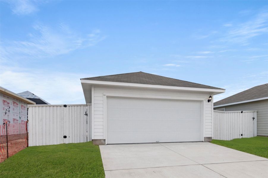 View of front of house featuring a shingled roof, an outbuilding, and a gate