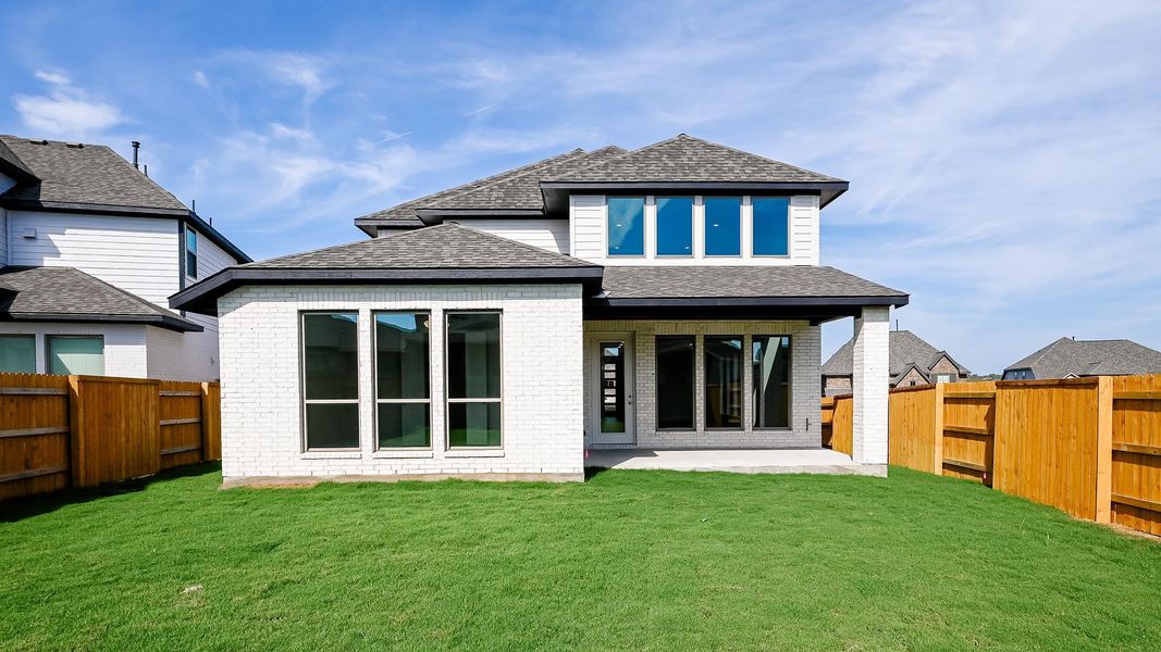 Rear view of property with a fenced backyard, a patio, roof with shingles, and brick siding