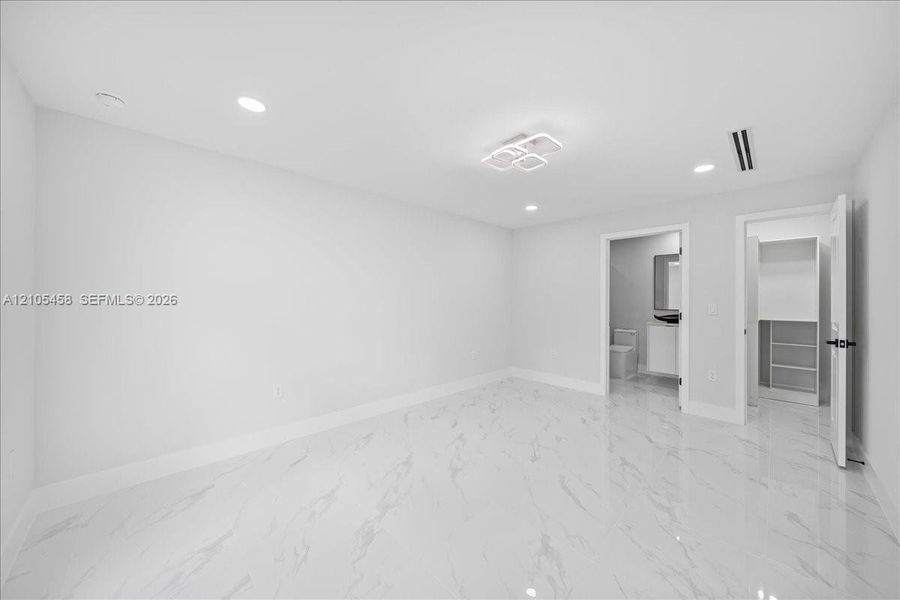 Recessed lighting, contemporary ceiling fixture, polished tile flooring, built-in closet shelving, and a white vanity with a rectangular mirror Recessed lighting, contemporary ceiling fixture, polished tile flooring, built-in closet shelving, and a white vanity with a rectangular mirror