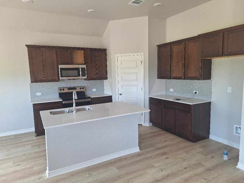 Kitchen with stainless steel appliances, tasteful backsplash, light wood-style flooring, and light countertops Kitchen with stainless steel appliances, tasteful backsplash, light wood-style flooring, and light countertops