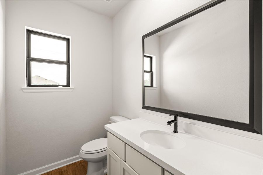 Bright and modern bathroom featuring sleek fixtures and a large mirror. Perfect for guests!