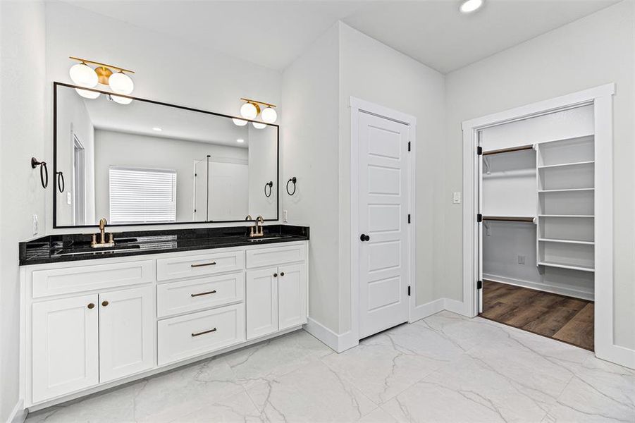 Bathroom with recessed lighting, light marble finish floors, double vanity, and a walk in closet Bathroom with recessed lighting, light marble finish floors, double vanity, and a walk in closet