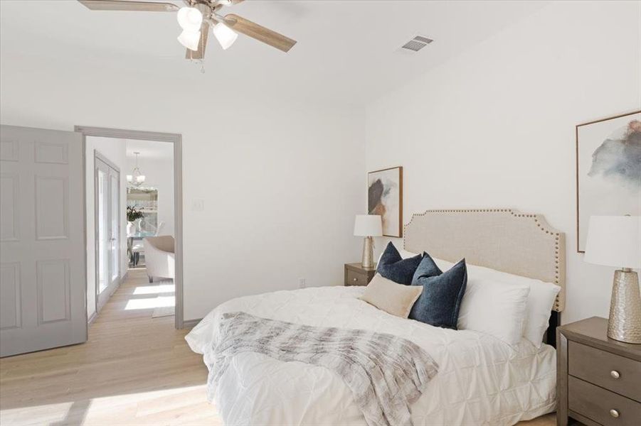 Bedroom with light hardwood / wood-style flooring and ceiling fan with notable chandelier