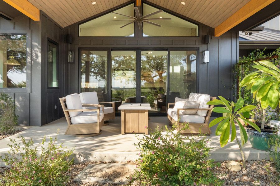 Covered patio featuring a slatted wood ceiling, exposed wood beams, and a large ceiling fan