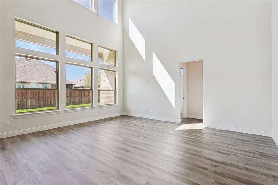 Unfurnished living room featuring hardwood / wood-style floors, a towering ceiling, and a healthy amount of sunlight