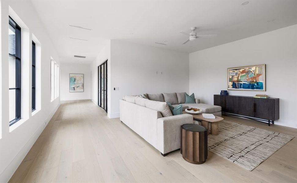 Living room with light wood-type flooring, ceiling fan, visible vents, and baseboards