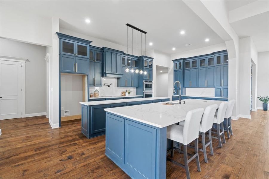 Kitchen featuring blue cabinets, a center island with sink, and sink