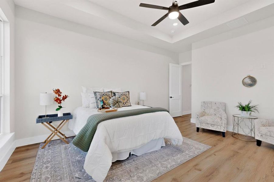 Bedroom with wood finished floors, a ceiling fan, and a raised ceiling