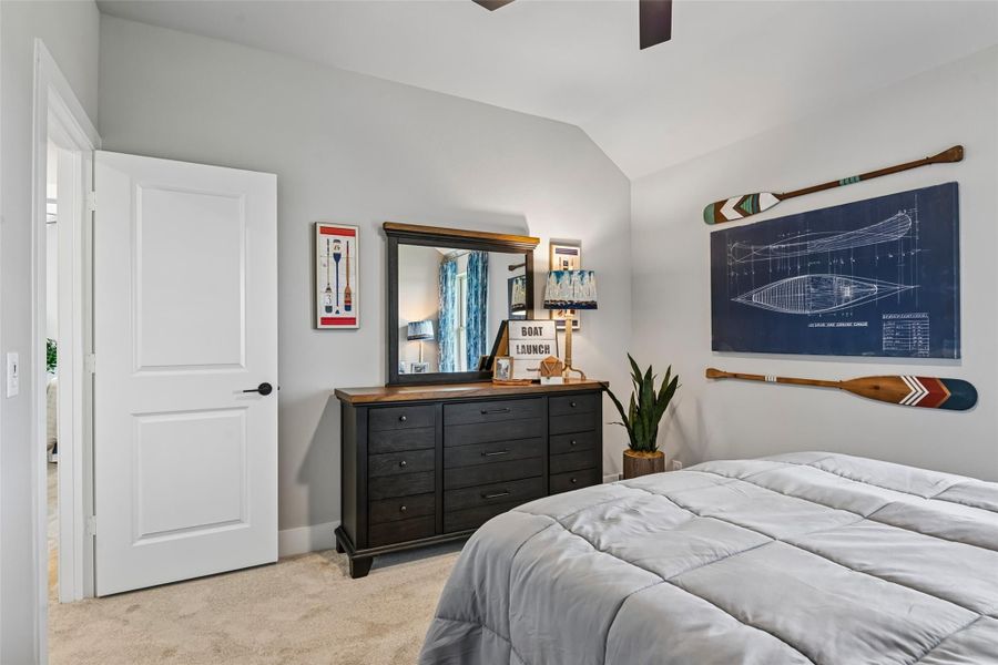 Bedroom with vaulted ceiling, dark wood dresser, and nautical wall decor including oars and boat blueprint art Bedroom with vaulted ceiling, dark wood dresser, and nautical wall decor including oars and boat blueprint art