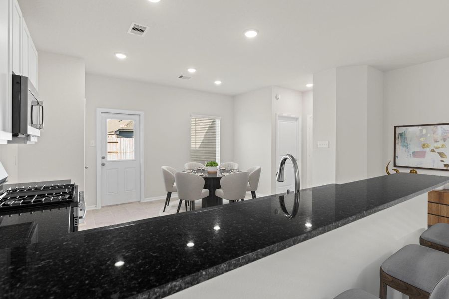 The virtually staged kitchen view shows a perfect balance of elegance and practicality. Granite countertops, stainless-steel appliances, and a breakfast bar create a beautiful yet functional space for cooking and entertaining.