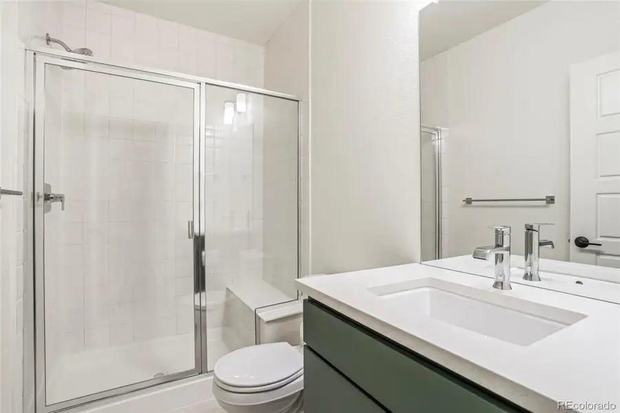 Modern bathroom with quartz countertop vanity, sleek fixtures, and glass-enclosed walk-in shower, offering clean, elevated finishes in this Morrison Colorado home