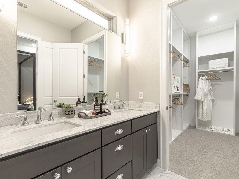 Primary en suite bath with dual vanities and large walk in closet with custom built-ins.