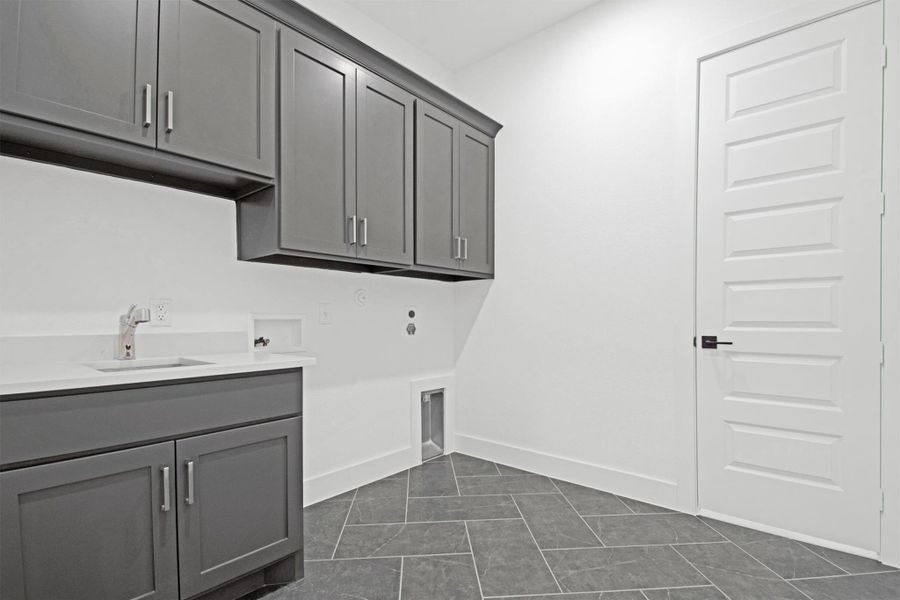 Laundry room with hookup for a washing machine, cabinet space, dark tile patterned floors, and hookup for a gas dryer