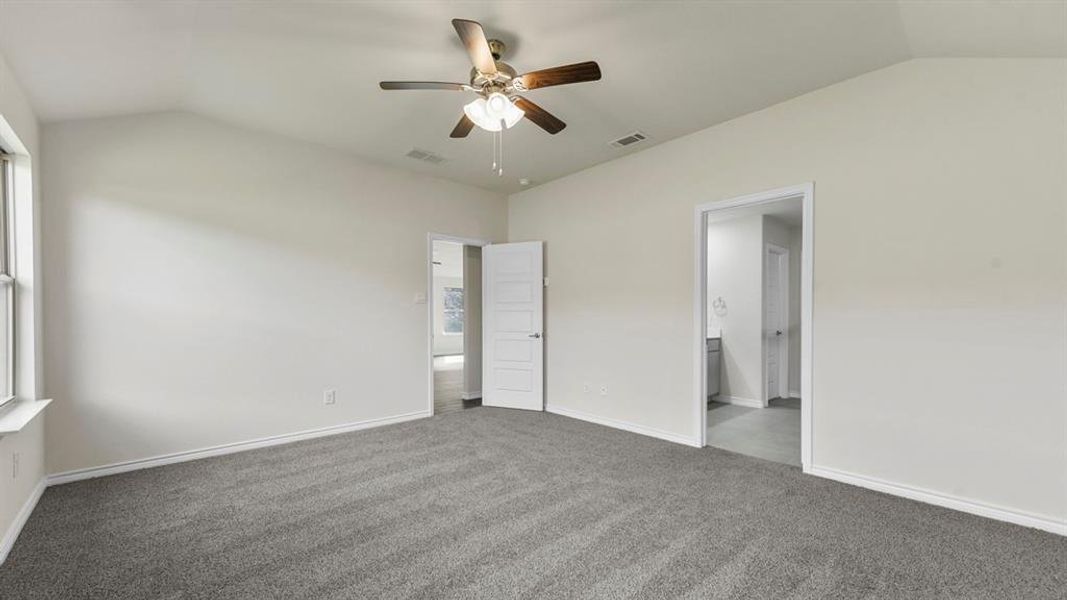 Carpeted room with a vaulted ceiling, a ceiling fan with integrated lighting, and white trim