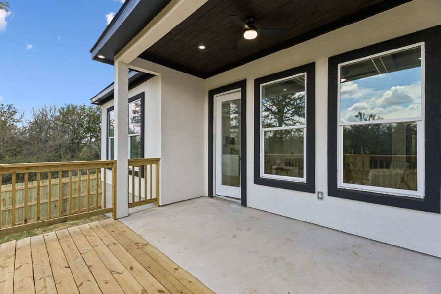 An inviting covered patio steps down to a wooden deck overlooking the backyard.