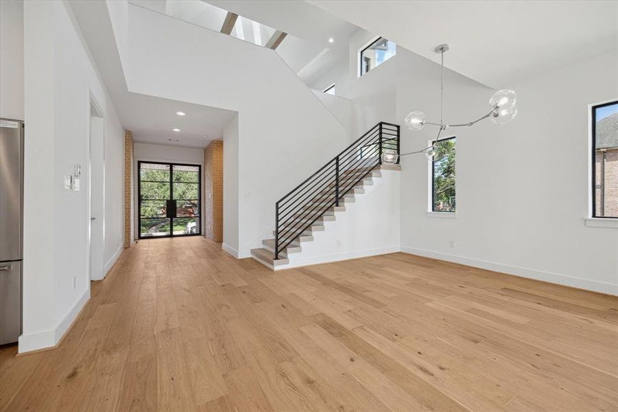 Looking toward front entry and stairs from dining area with a glimpse of the expansive vaulted ceiling over the loft space above.