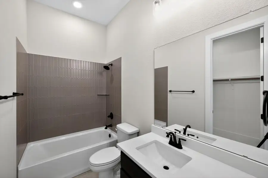 Full bathroom featuring shower / tub combination, vanity, and a spacious closet Full bathroom featuring shower / tub combination, vanity, and a spacious closet