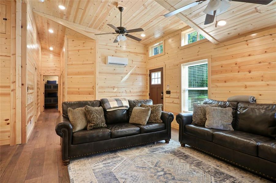 Living room featuring wood walls, ceiling fan, hardwood / wood-style floors, and wooden ceiling