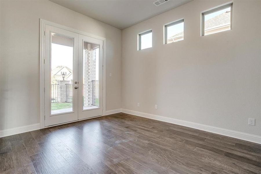 Unfurnished room with dark hardwood / wood-style floors, plenty of natural light, and french doors