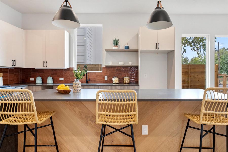 Kitchen with a kitchen breakfast bar, tasteful backsplash, open shelves, and dark countertops Kitchen with a kitchen breakfast bar, tasteful backsplash, open shelves, and dark countertops