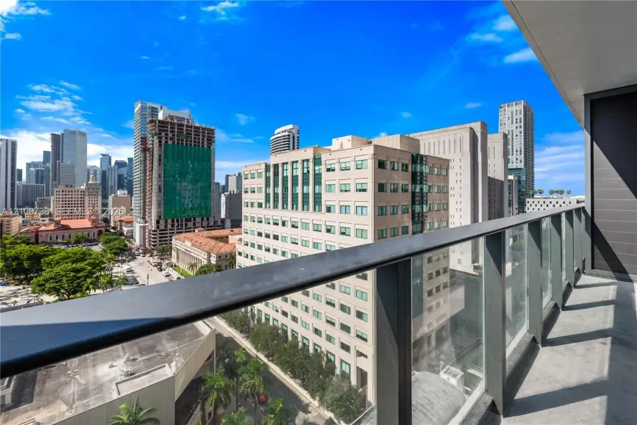 Private balcony featuring a glass panel railing, metal top rail, and concrete flooring Private balcony featuring a glass panel railing, metal top rail, and concrete flooring