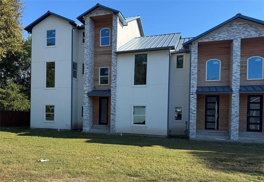 View of front of house featuring a front lawn, a standing seam roof, a metal roof, and stone siding