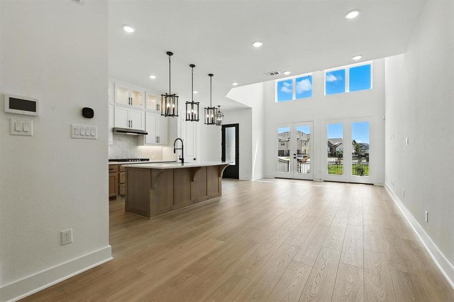 Kitchen featuring glass insert cabinets, pendant lighting, backsplash, recessed lighting, and brown cabinets Kitchen featuring glass insert cabinets, pendant lighting, backsplash, recessed lighting, and brown cabinets