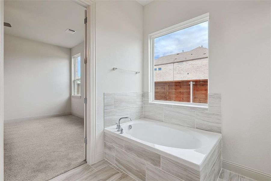 Bathroom with plenty of natural light, tiled bath, and hardwood / wood-style floors