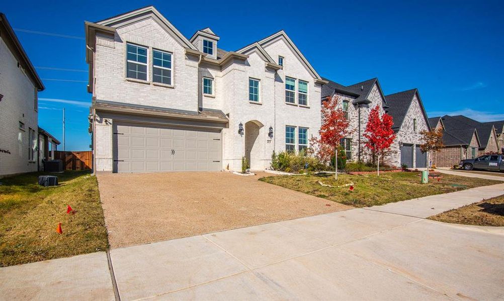 View of front of home featuring a garage, central air condition unit, and a front lawn