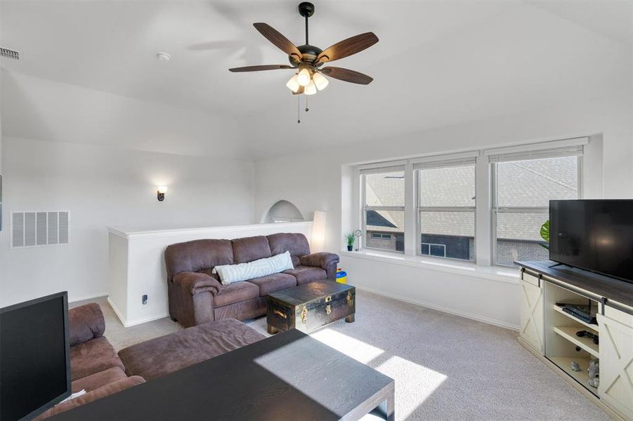 Living room featuring ceiling fan, light colored carpet, and lofted ceiling