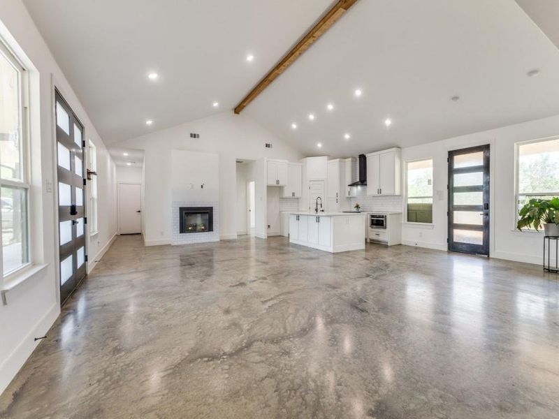 living room with beam ceiling, a sink, french doors, a glass covered fireplace, and high vaulted ceiling